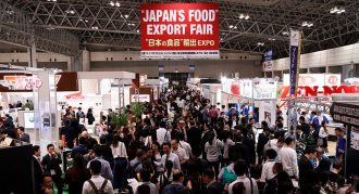 A busy trade expo centre with a sign hanging above which reads 'Japan's Food Export Fair''