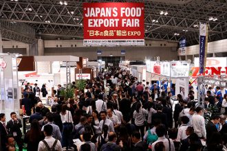 A busy trade expo centre with a sign hanging above which reads 'Japan's Food Export Fair''