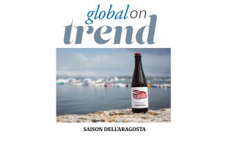 A bottle of Saison dell’Aragosta on a wall with a marina in the backgound