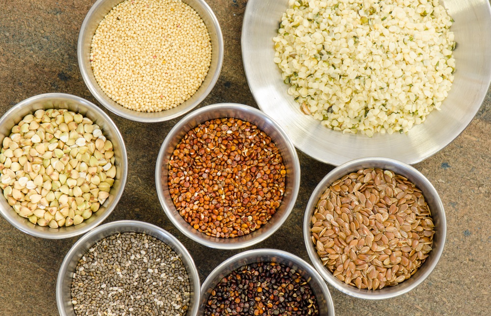Ancient grains and healthy organic edible seeds in round stainless steel containers. These are considered superfoods.