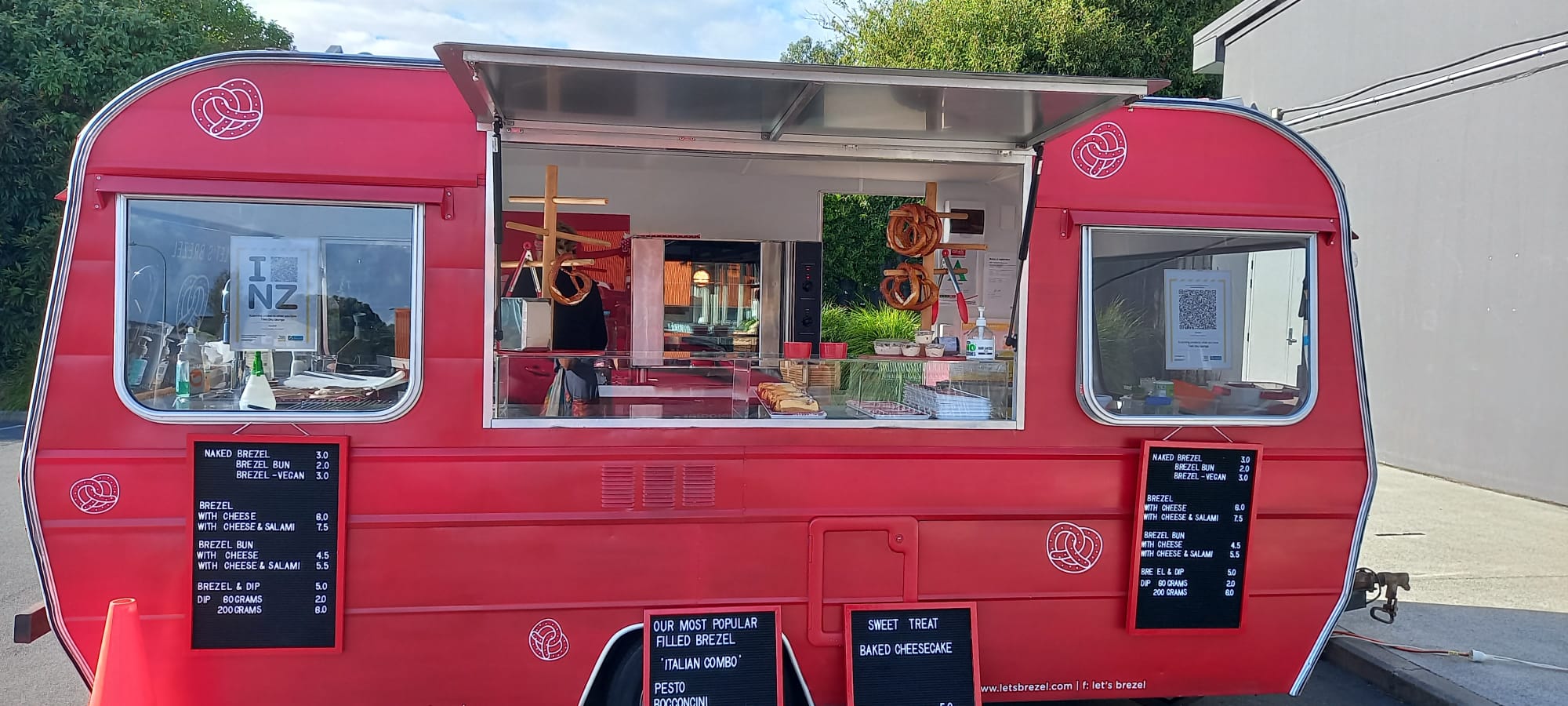 red caravan food truck with four black chalk board signs and white chalk writing of menu