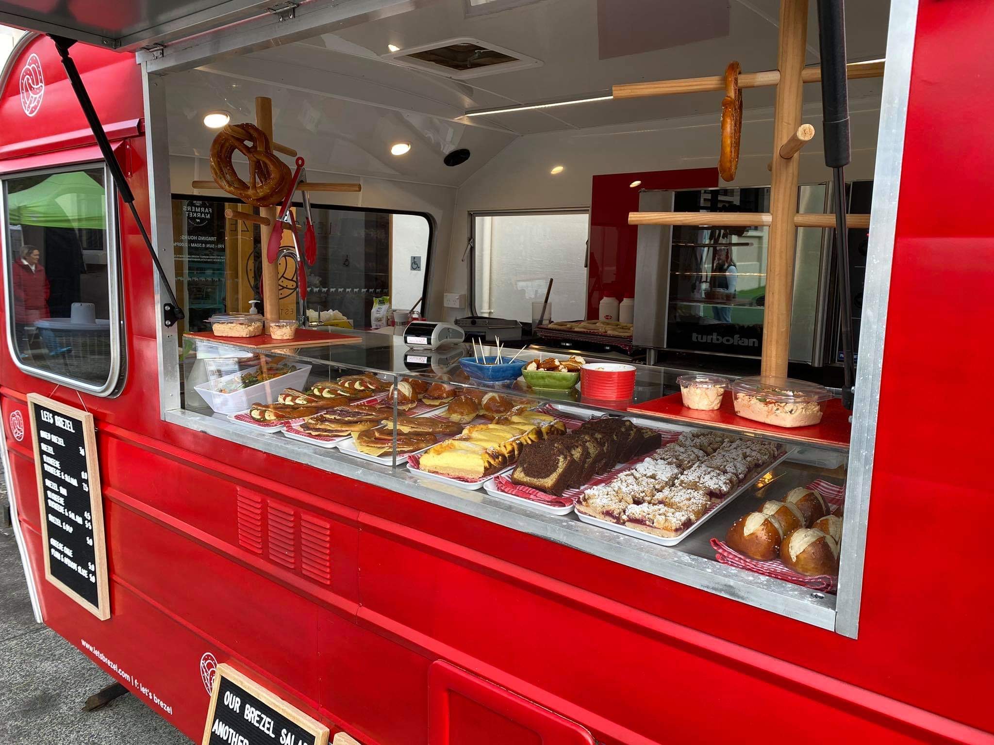red food truck with pretzels on display and menu sign