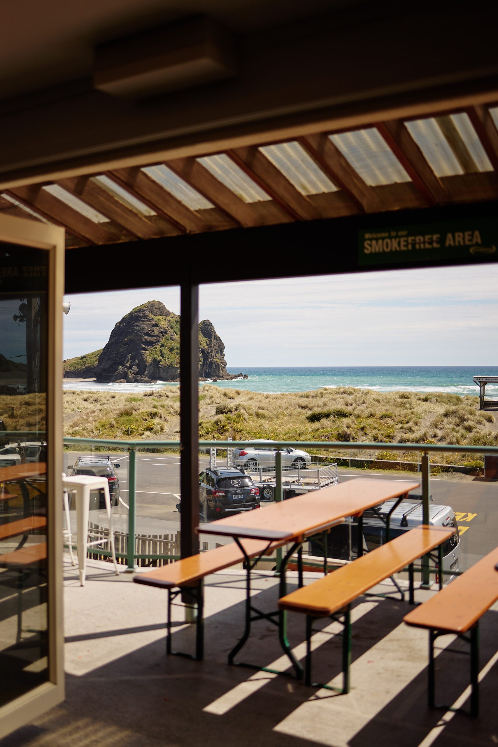 table and bench with view of the beach and rock at Piha
