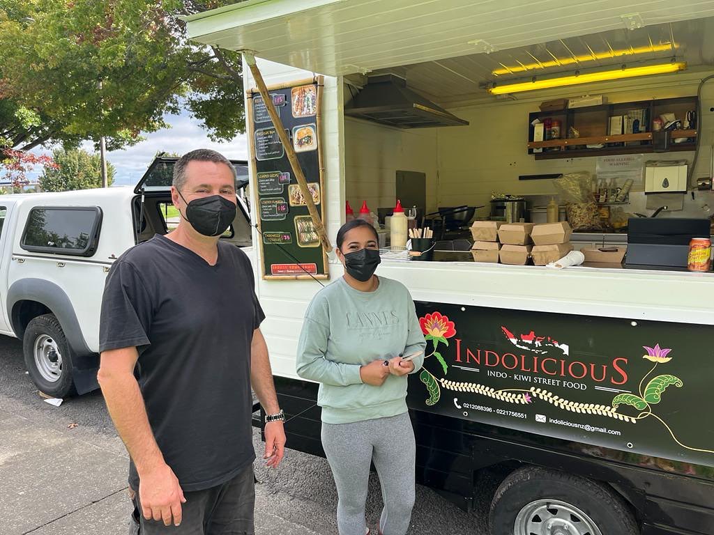 Owner of food truck and customer standing outside food truck