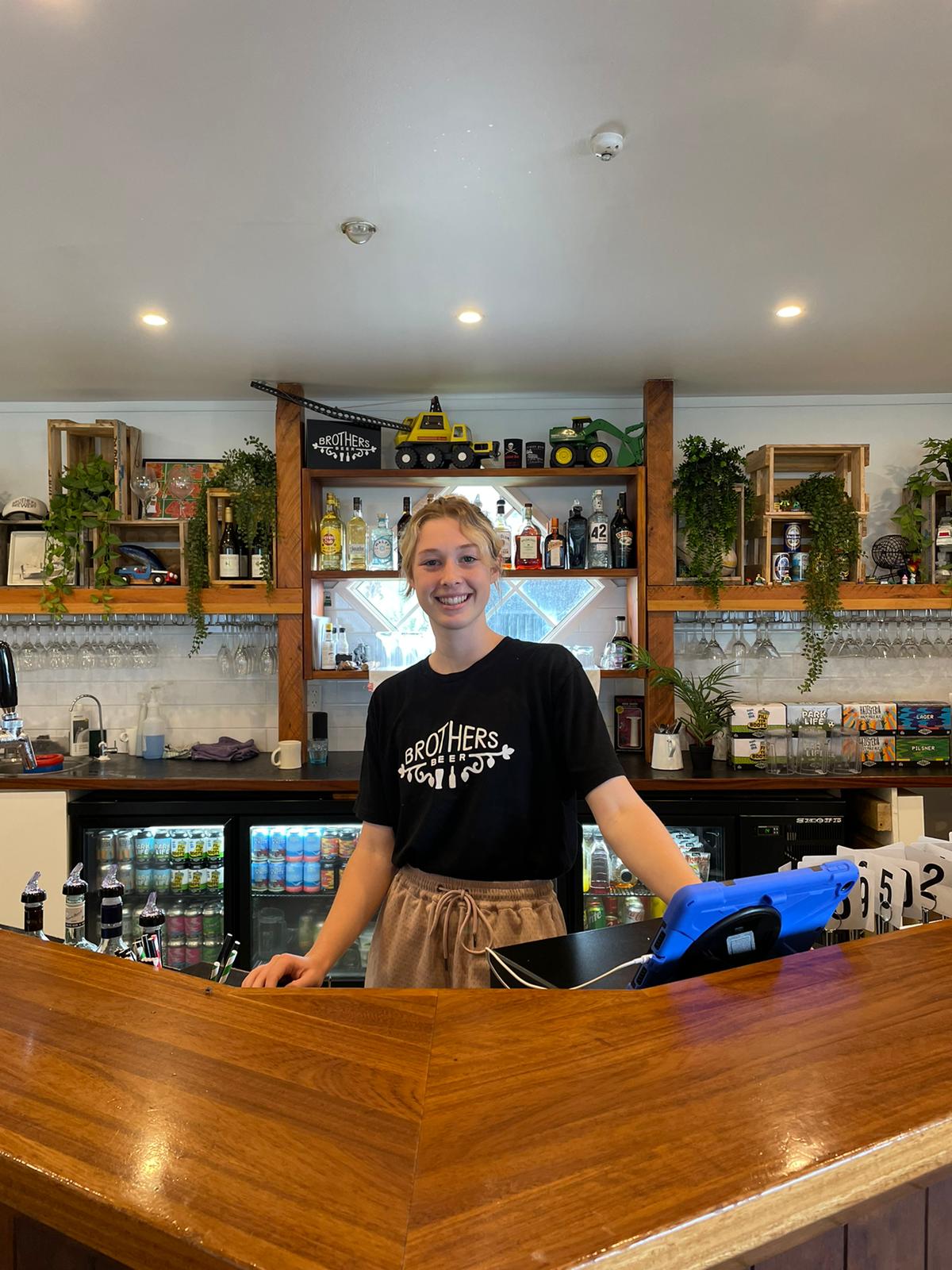 smiling female bartender behind bar bench