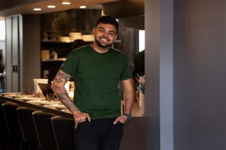 Man (chef owner) standing in mid view and smiling in front of restaurant