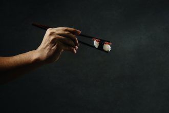 hand holding chopsticks and salmon sushi