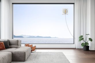 Landscape image of WINBOT W1 PRO cleaning a large window with a scenic lake view.