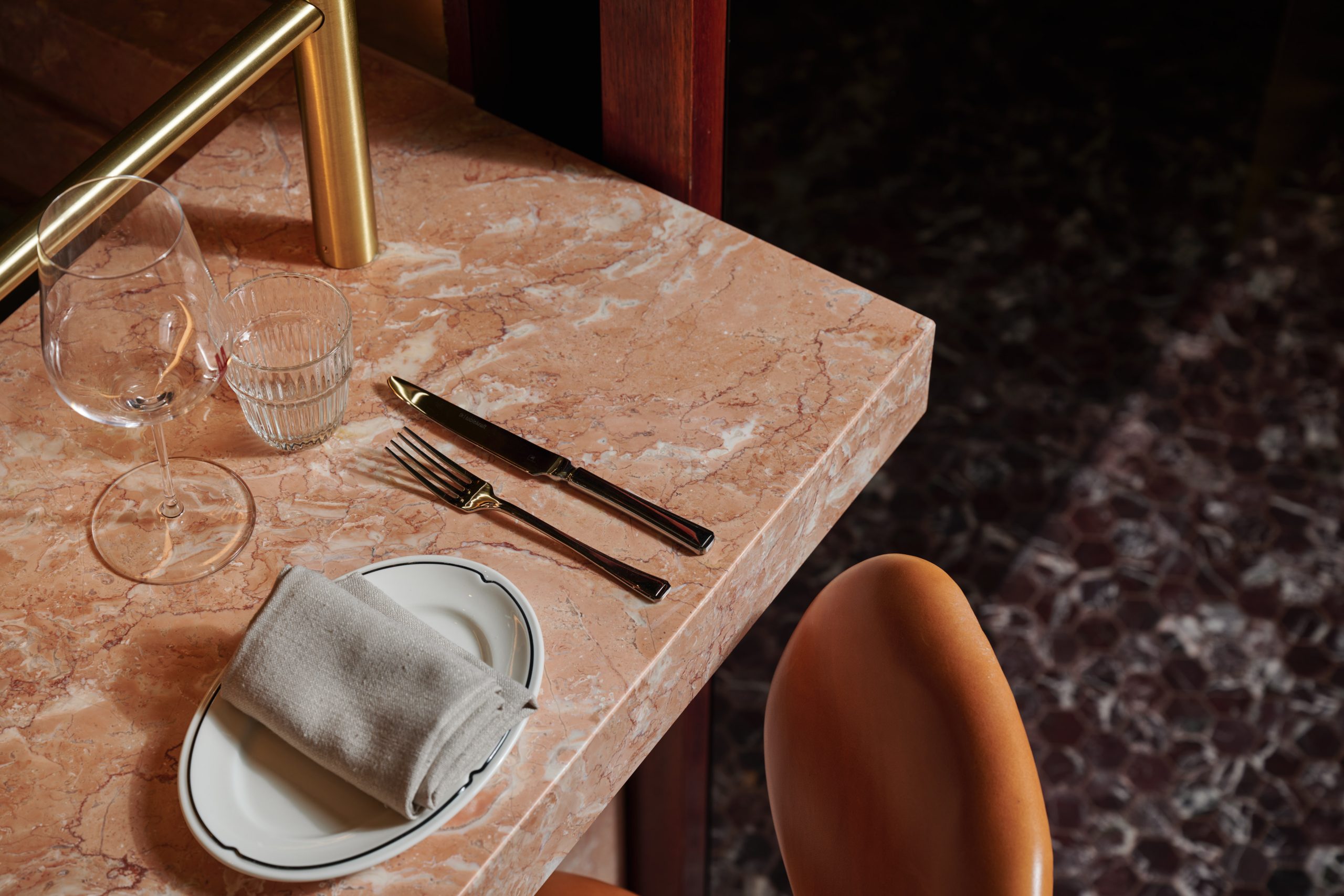 Close up of peach marble bar top, set with cutlery for service.